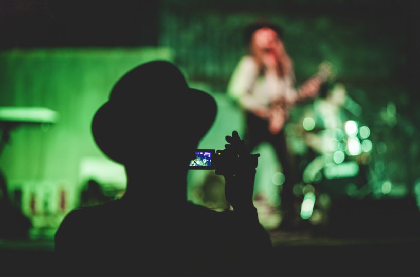 Man in hat recording video at gig - Choosing the best video camera for beginners