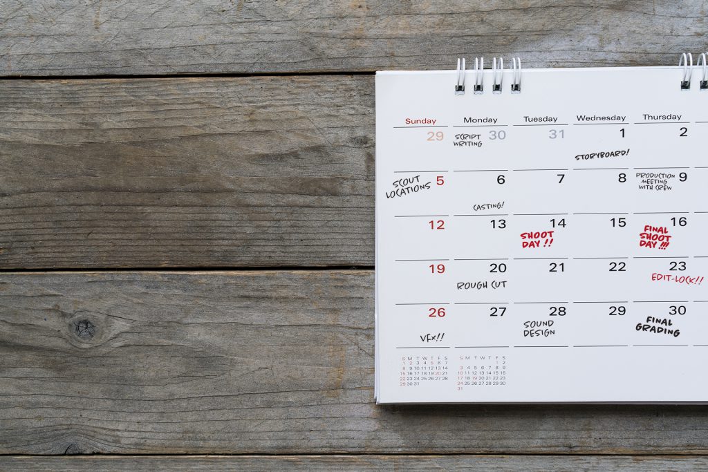 Calendar on washed oak table with production days scheduled in in pen