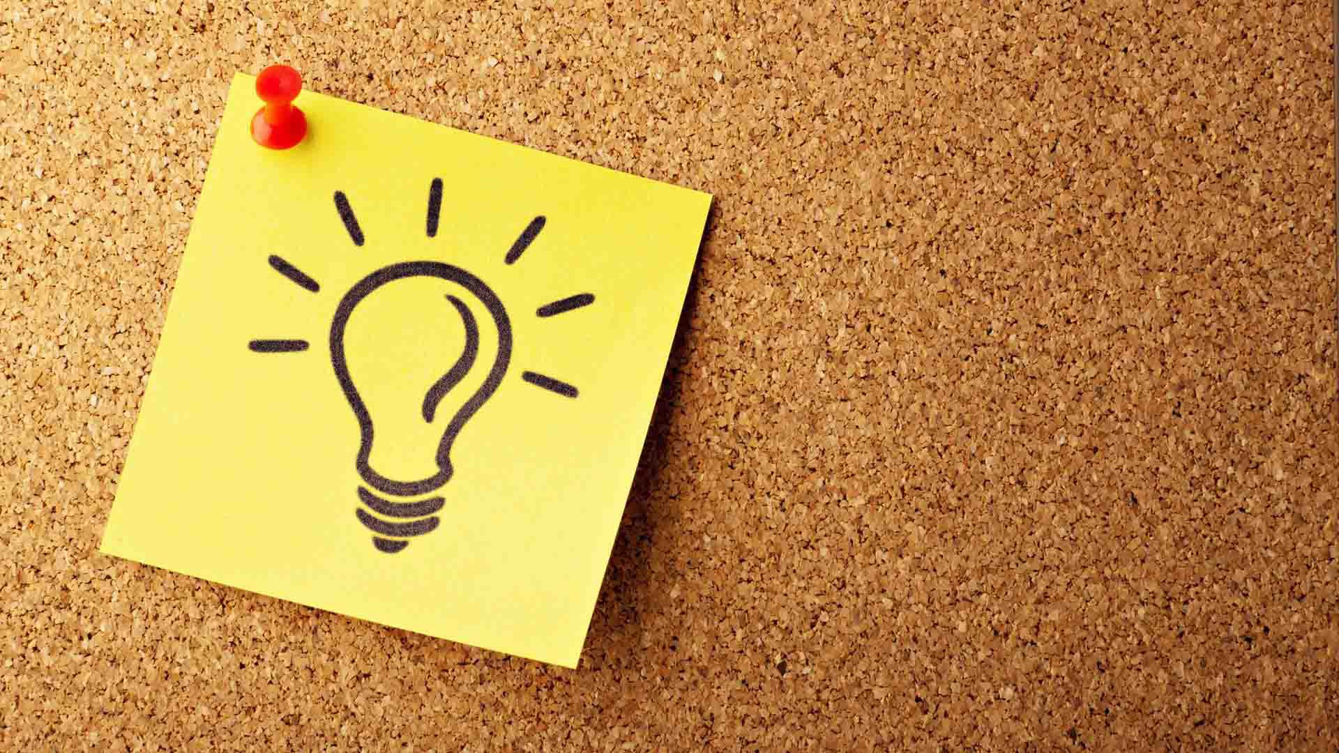 idea generation - post-it note with lightbulb drawn on it on cork ideas board
