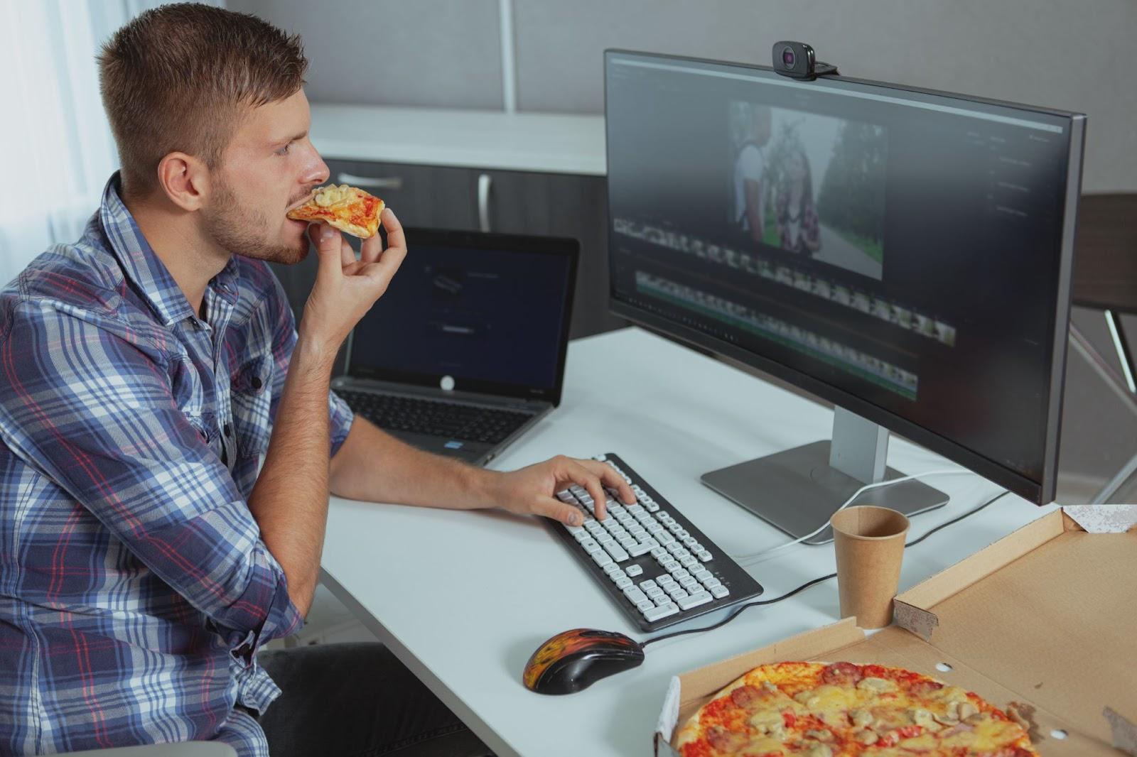 Editor eating pizza at computer desk